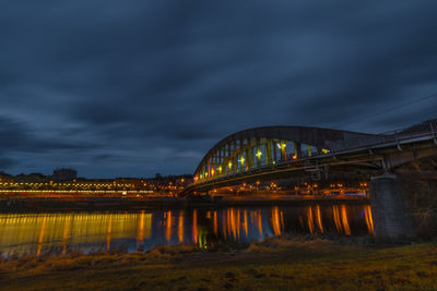 Illuminated bridge over river against sky at night