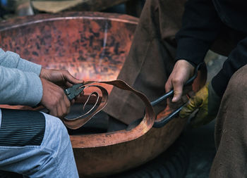 Midsection of man working on copper 