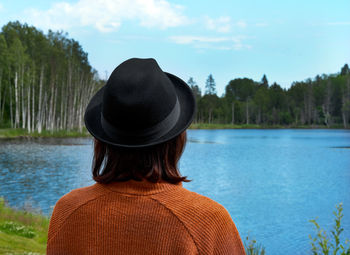 Unrecognizable woman full of thoughts wearing hat and sweater standing in front of karelia lake 