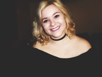 Portrait of smiling young woman with blond hair at home