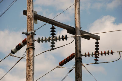 Low angle view of power lines against cloudy sky