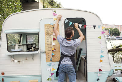 Rear view of male owner hanging bunting on food truck