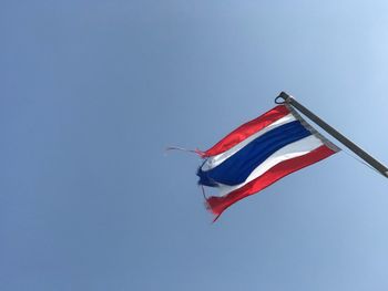 Low angle view of flag against clear blue sky