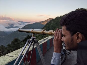 Young man looking at view through telescope