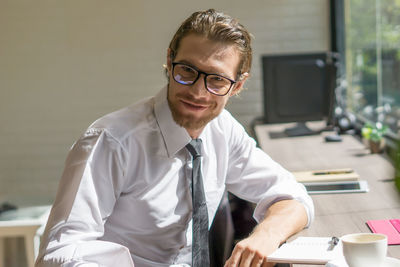 Portrait of young businessman wearing eyeglasses while sitting in office