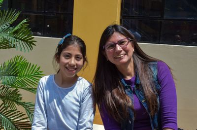 Portrait of smiling mother and daughter against wall