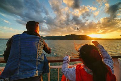 Man feeding seagull with his daughter from yacht railing