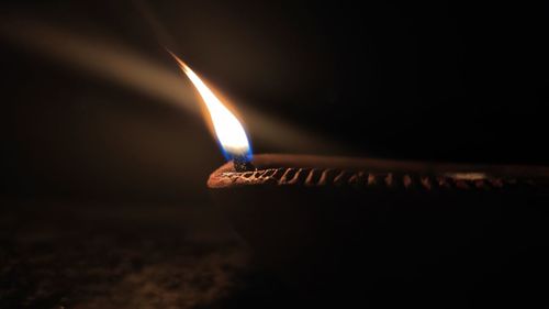 Close-up of lit candle in darkroom