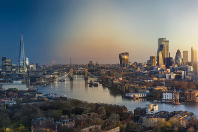 River amidst buildings against sky during sunset