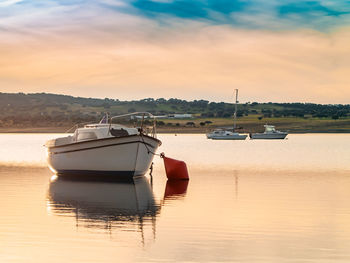 Boat moored in lake against sky during sunset