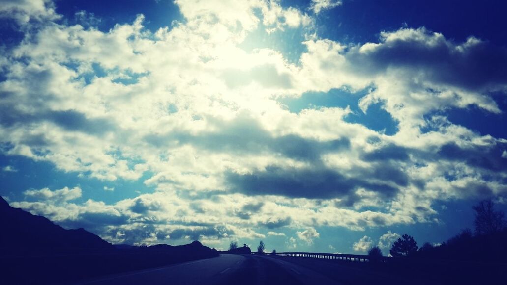 sky, cloud - sky, the way forward, cloud, transportation, cloudy, road, tranquility, tranquil scene, scenics, nature, beauty in nature, diminishing perspective, blue, mountain, vanishing point, silhouette, landscape, outdoors, no people