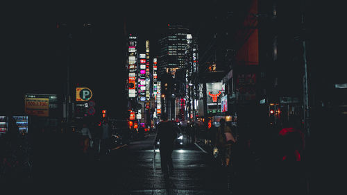 Illuminated city street amidst buildings at night