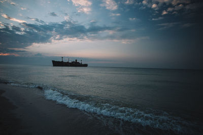 Boat sailing on sea against sky during sunset