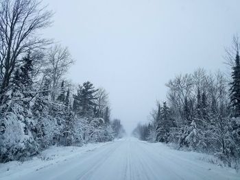 Road amidst bare trees against clear sky during winter