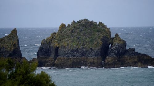 Scenic view of sea by cliff against clear sky