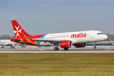 Red airplane on airport runway against sky