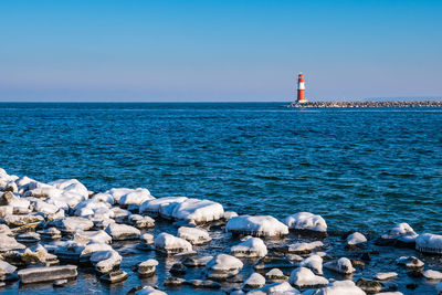 Lighthouse by sea against sky