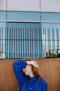 Portrait of girl wearing mask against blue wall