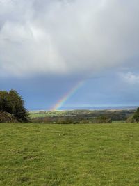 Scenic view of field against rainbow in sky