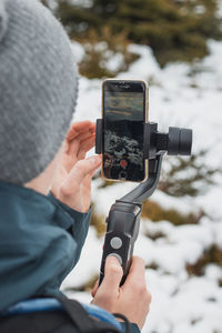 Midsection of person photographing with mobile phone in winter