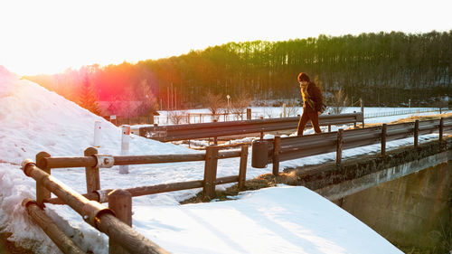 Man standing by railing against sky during winter