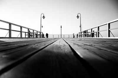 People walking on bridge against clear sky