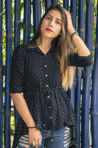 Portrait of young woman standing against bamboo