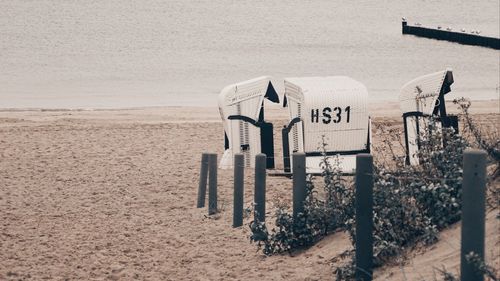 Hooded chairs on beach against sky