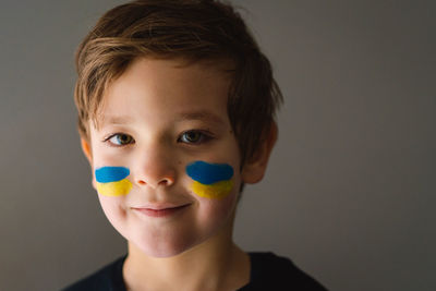 Portrait of a ukrainian boy with a face painted with the colors of the ukrainian flag.