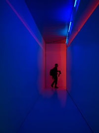 Silhouette man standing on illuminated corridor of building