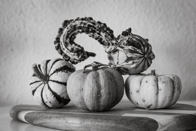 A selection of colourful and varied mini pumpkin decorations presented on a wooden chopping board