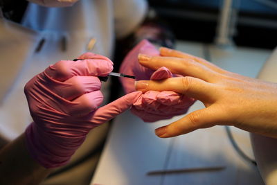 Midsection of beautician applying nail polish on female customer in salon