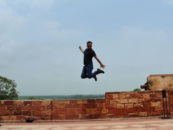 Full length of man jumping against sky