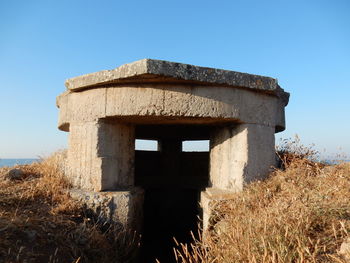 Old ruin building on field against clear blue sky