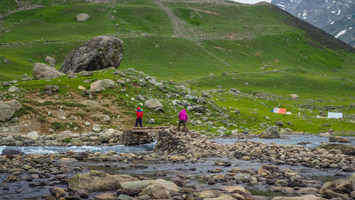 People on rock by mountain against sky