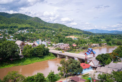 High angle view of houses and trees by mountains against sky