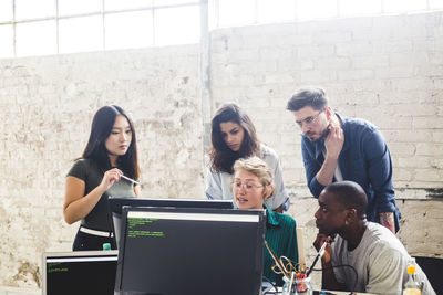 Confident young professionals planning while coding in computer at workplace