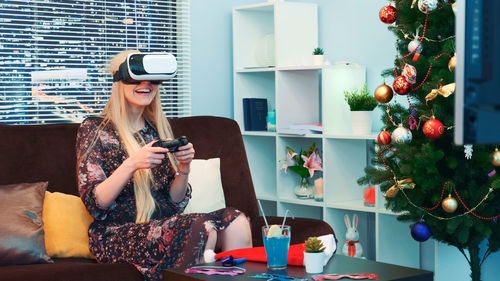 Portrait of young woman using mobile phone while sitting at home