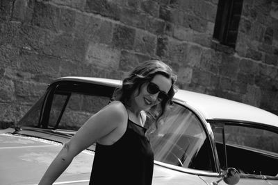 Portrait of smiling woman standing by car 