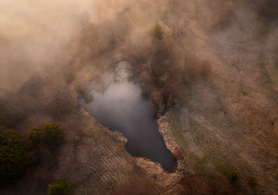 Fog rolling in on the pond. aerial drone view of a small pond with early morning fog. 