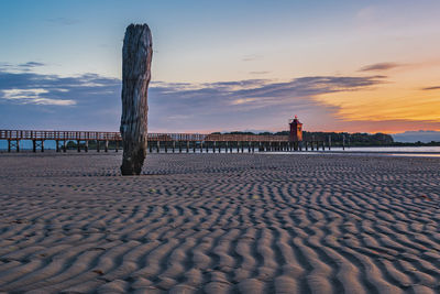 Sunrise over the sea. the lighthouse of lignano sabbiadoro and the games of sand and colors. italy