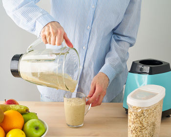 Midsection of man holding ice cream on table