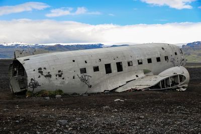 Abandoned airplane on airport runway against sky