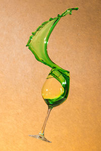 Close-up of green drinking splashing out of wineglass