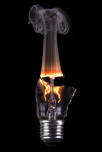 Close-up of smoke from broken light bulb over black background
