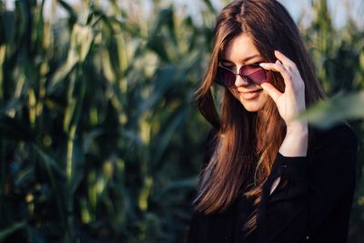 Young woman standing against crops on field