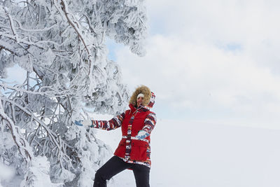 Full length of woman with arms outstretched standing on snow