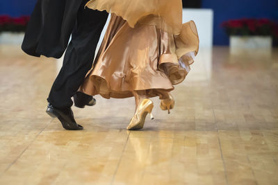 Low section of couple dancing on hardwood floor