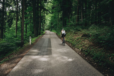 Woman riding her roadbike on road in forest in the austrian alps