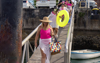Women in bikinis walking down a walkway to the pier. 